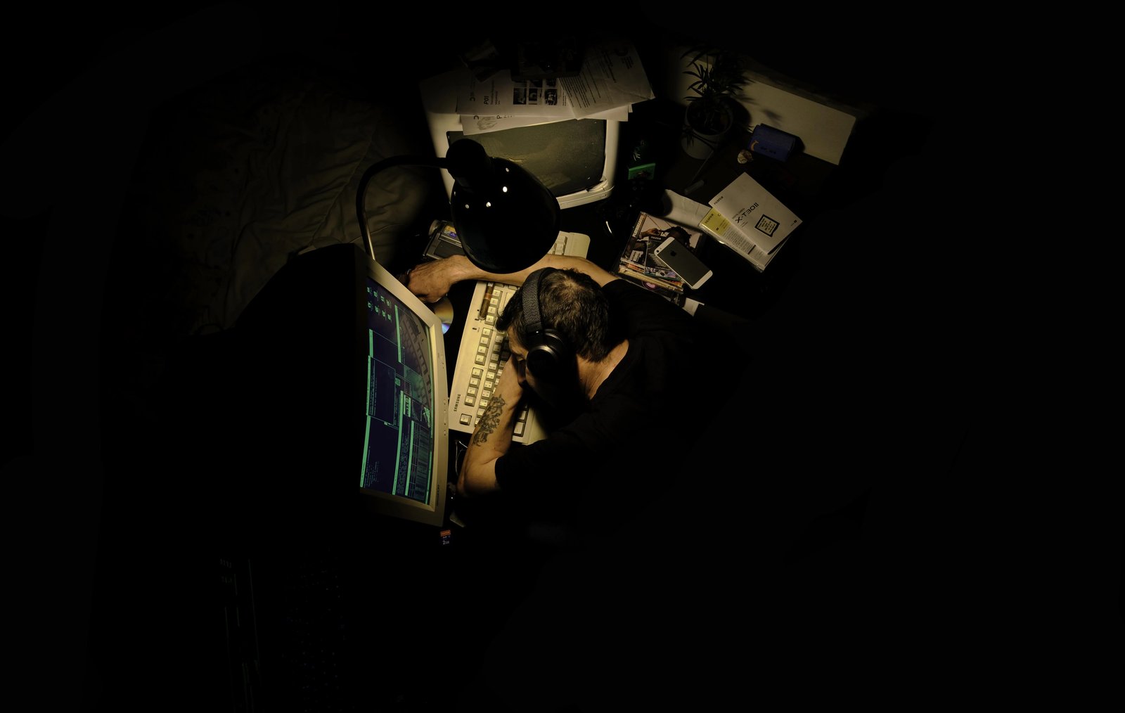 Overhead view of a hacker's desk, glowing terminal screen, headphones, and scattered cables
